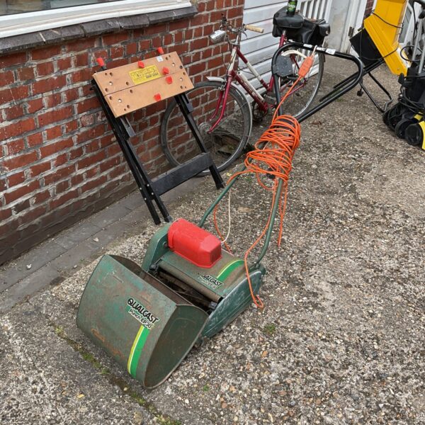Vintage Qualcast electric lawn mower in a garden setting.