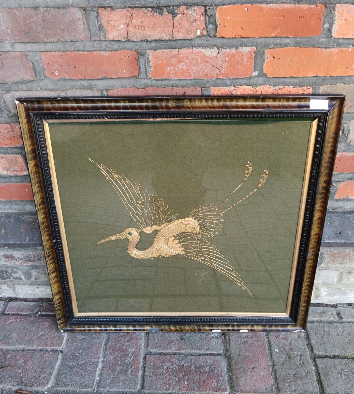 Gold thread embroidery of a crane bird in flight