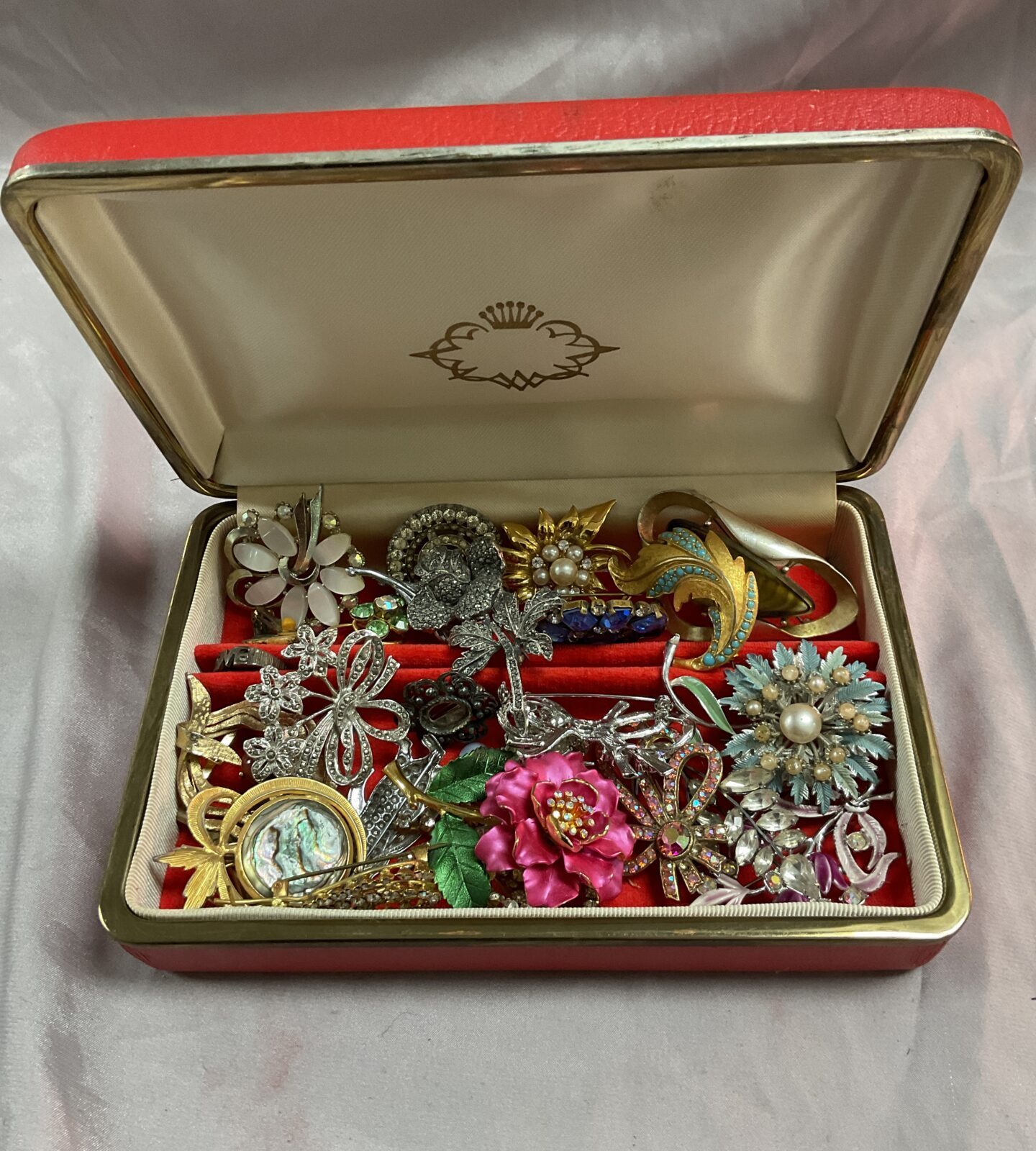 Red jewellery box of assorted brooches