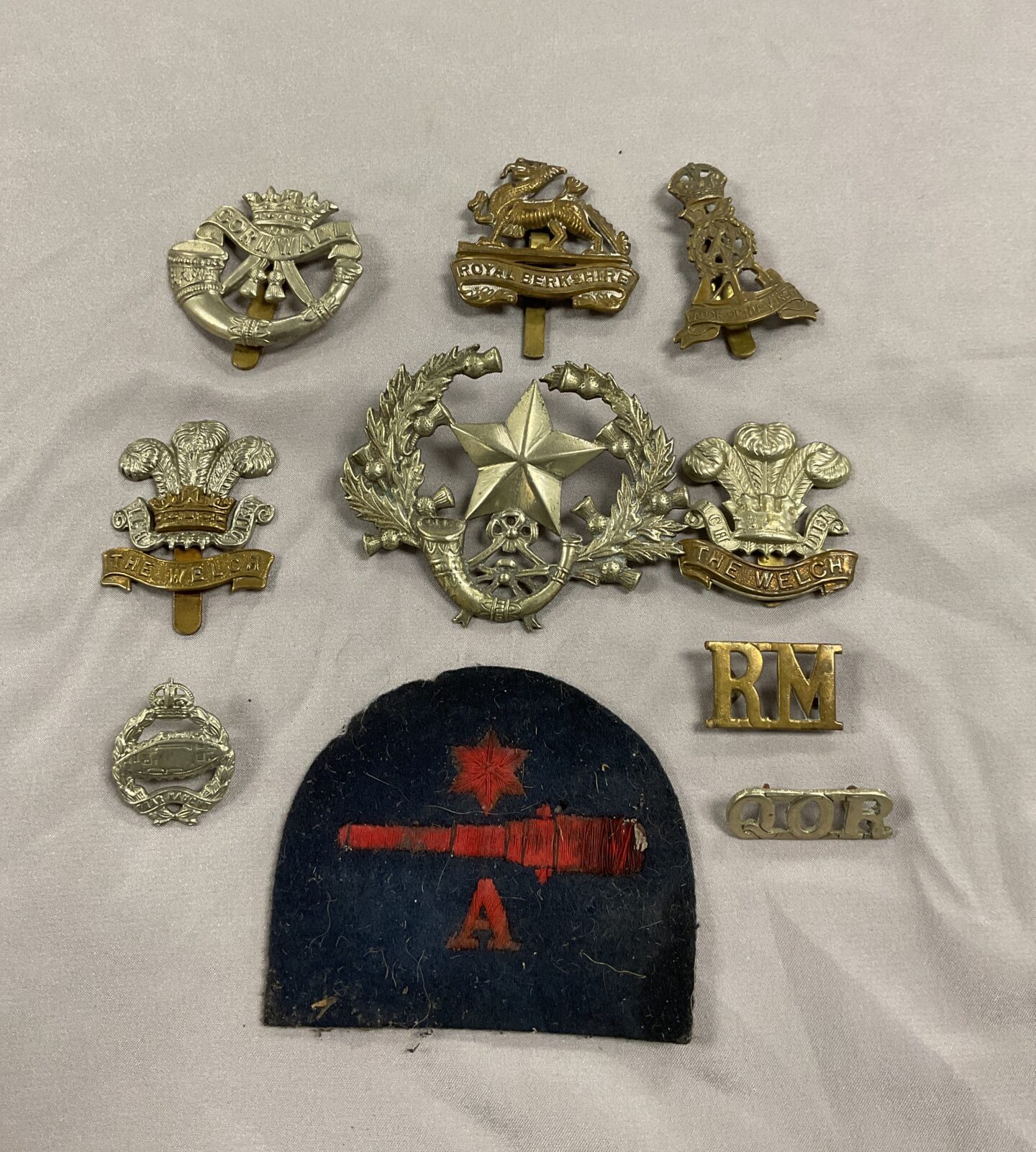 Collection of military cap badges and navy gunners patch