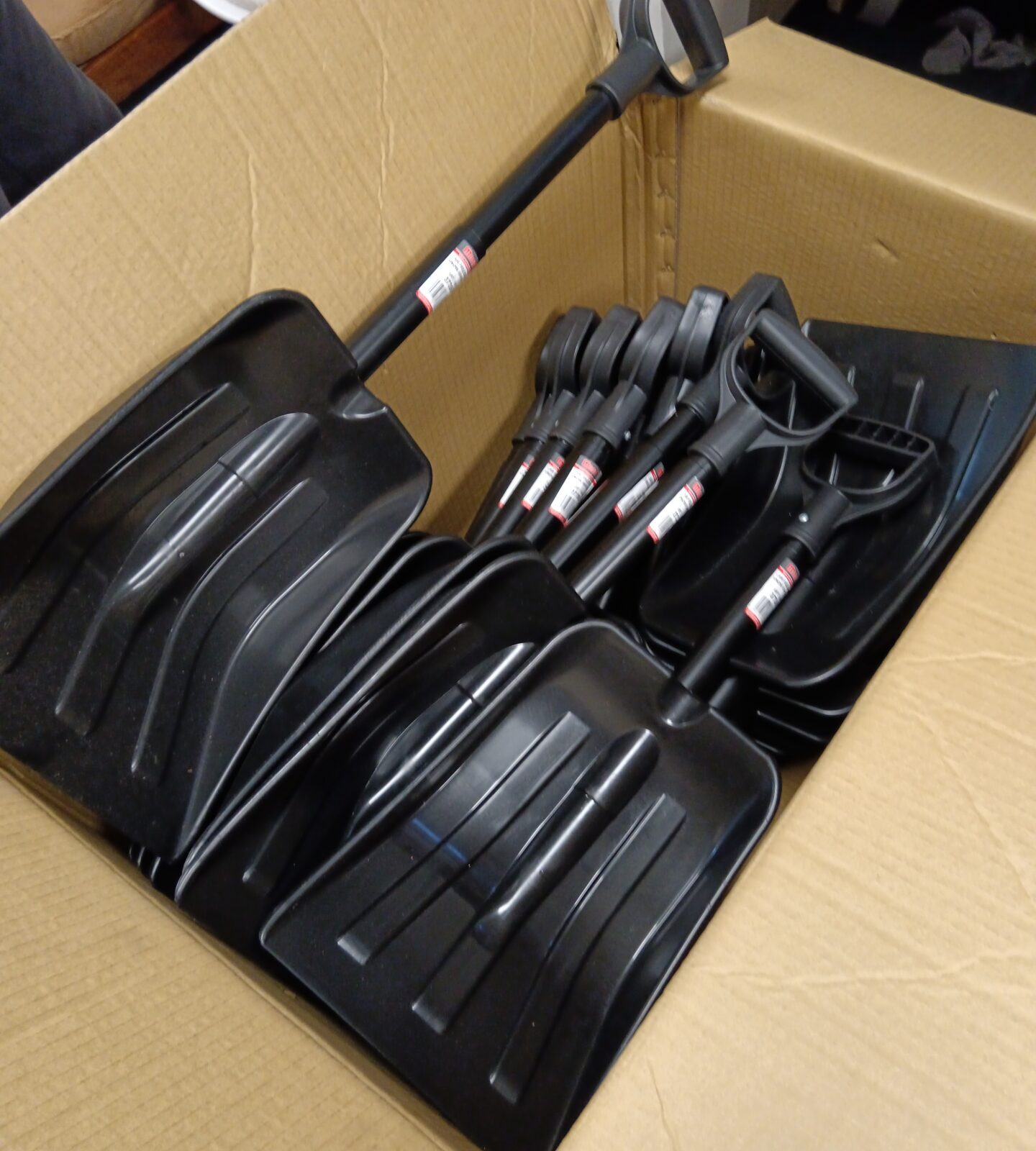 Large box of new folding snow shovels