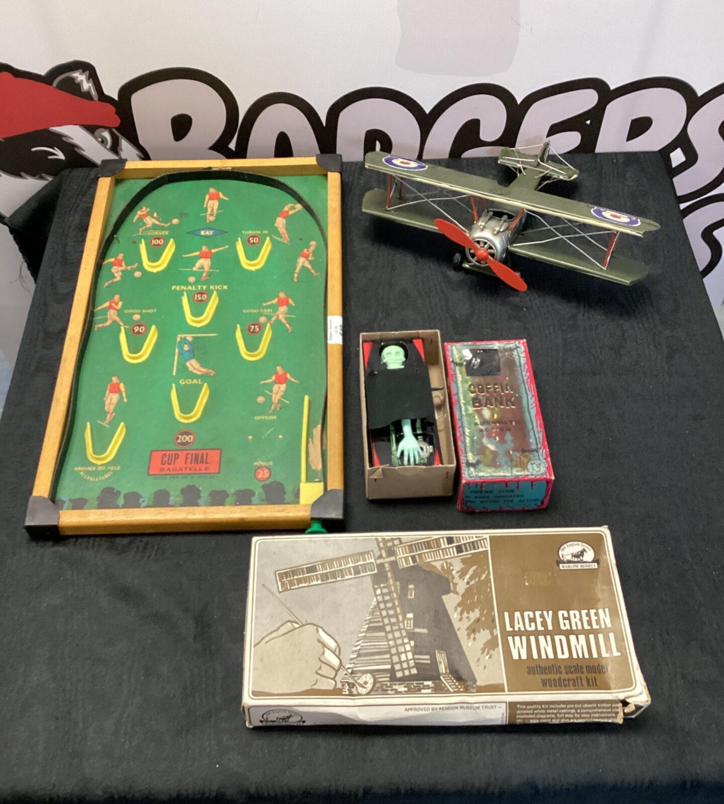 box of mixed inc vintage coffin bank, and a tin plate aeroplane F cup final bagatelle board