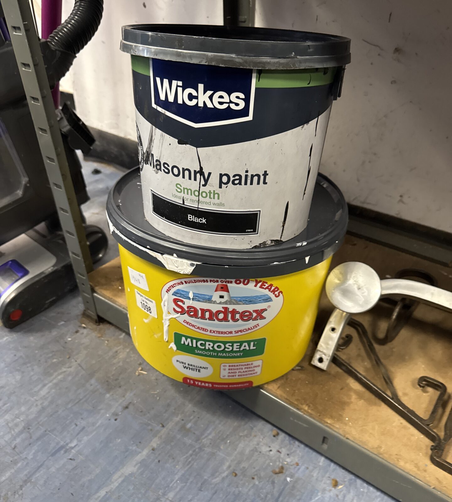 Wickes black masonry paint (feels 3/4 full) with tub of sandtex brilliant white (feels 1/2 full)