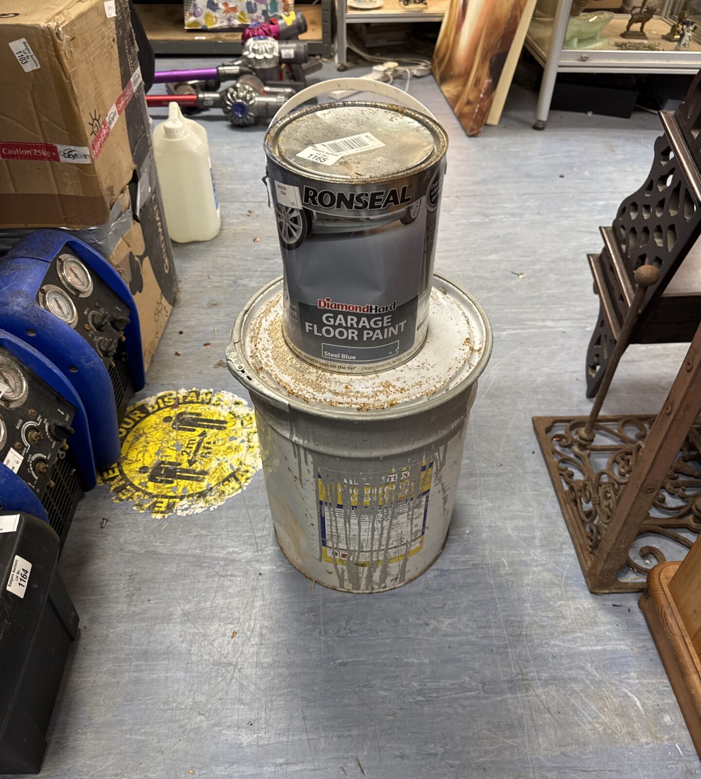 Two tins of grey floor paint - top tin feels half full, bottom one quarter full