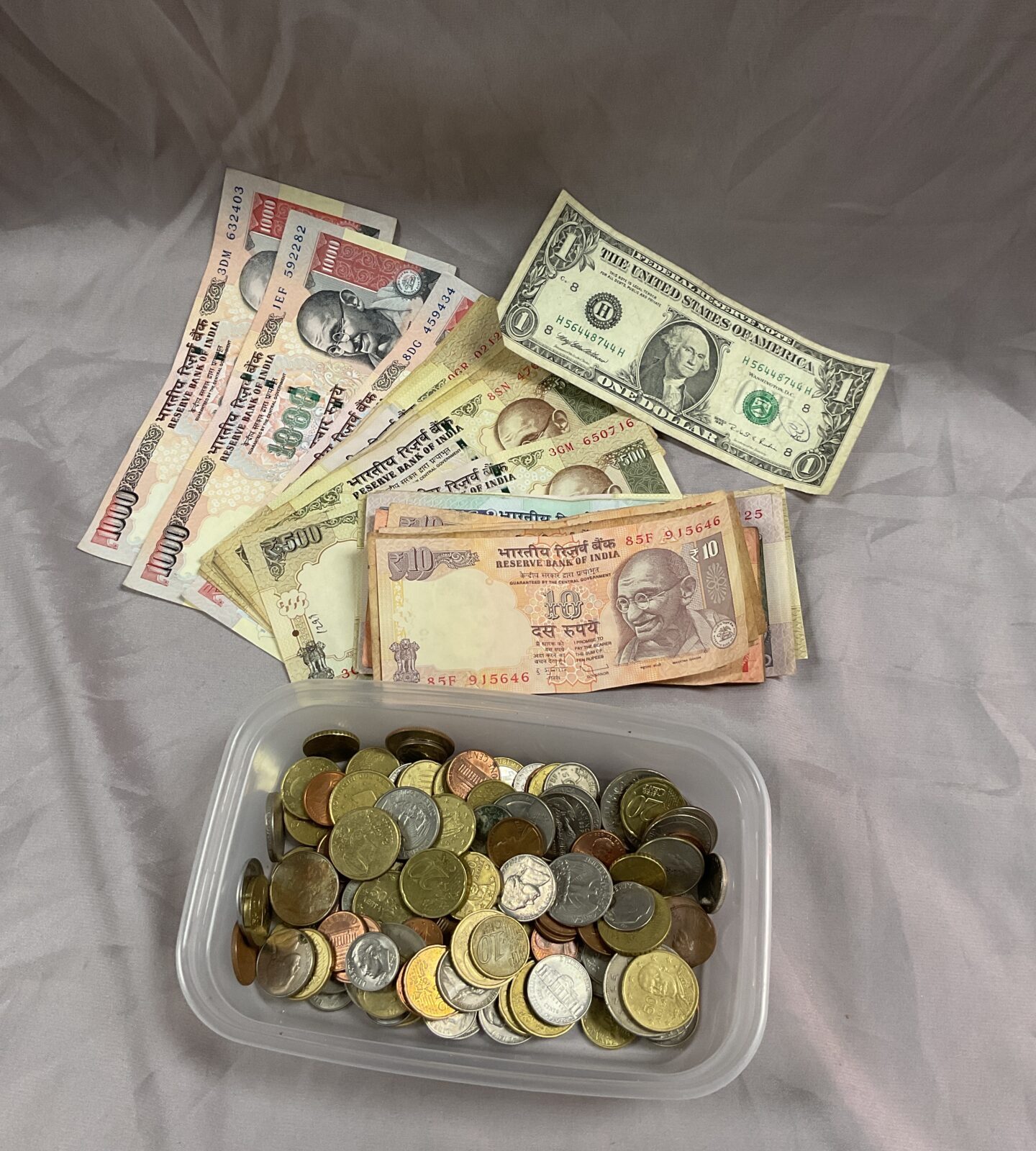 Tub of mixed euro coins and Indian notes