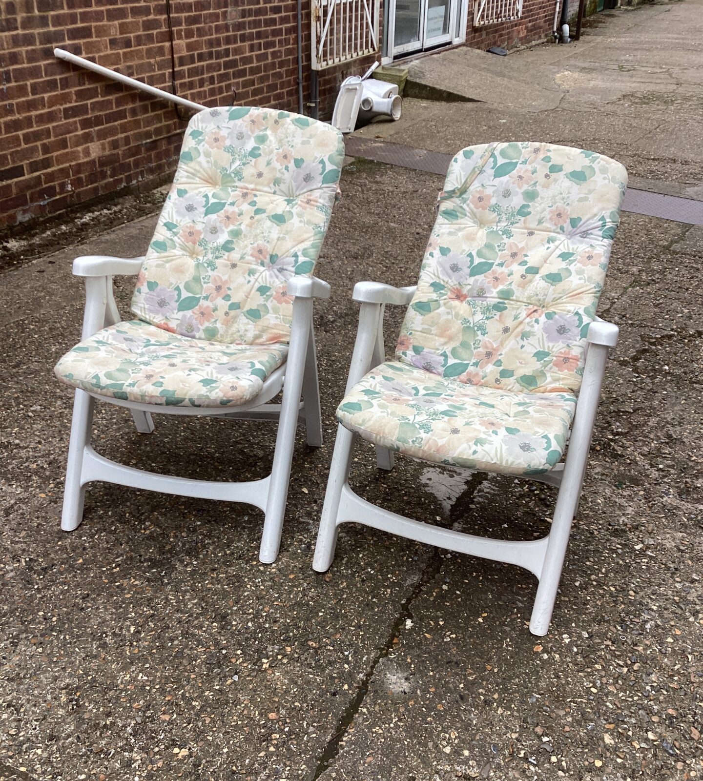 Two plastic garden chairs with cushions