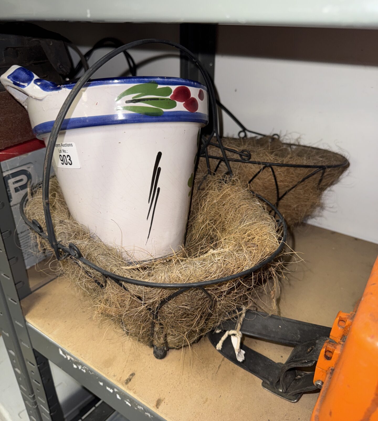 Two small lined wrought iron plant baskets with a decorative plant pot