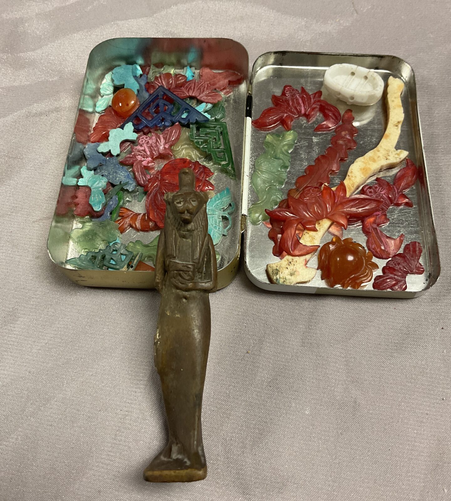 Tin of jadeite decorative items and Egyptian God Amulet?