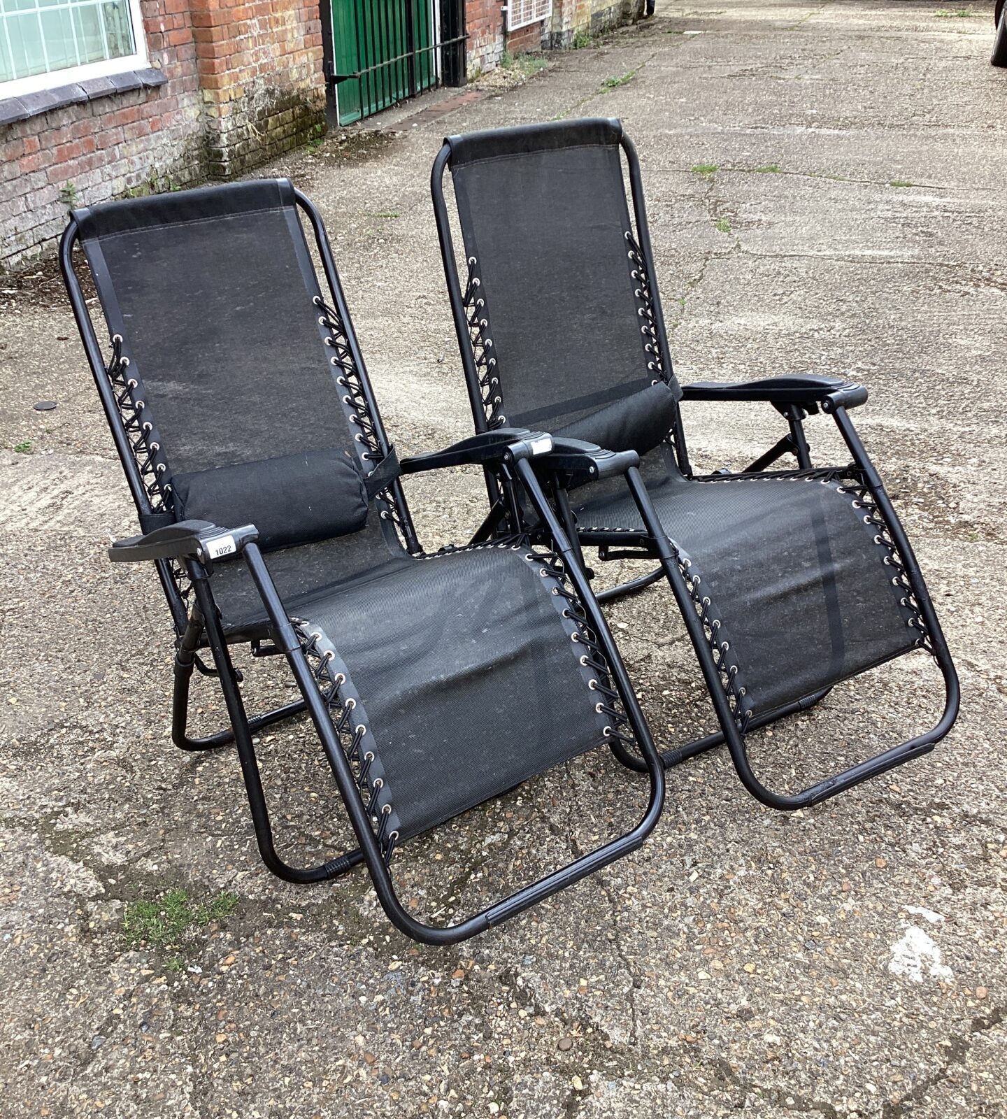 Two black folding garden sun loungers