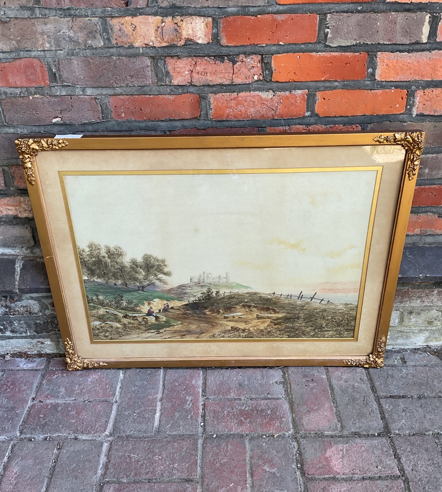 Large gilt framed watercolour of a castle on hill with figures signed