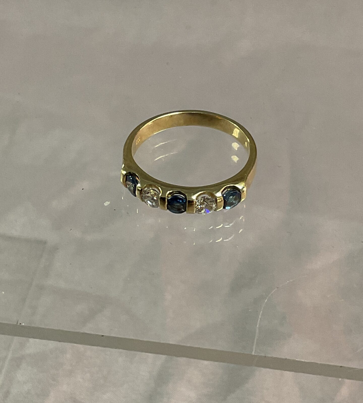 Silver gilt half eternity ring set with five blue and white stones