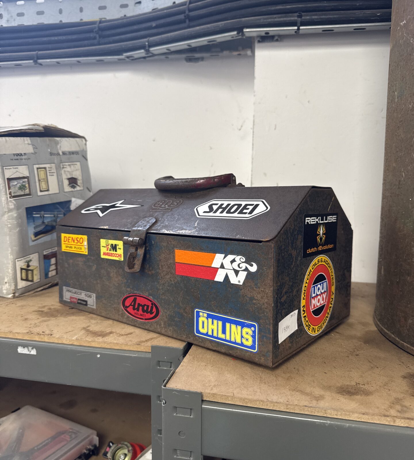 Small vintage metal toolbox with motorcycle related stickers