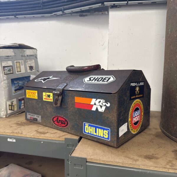 Small vintage metal toolbox with motorcycle related stickers
