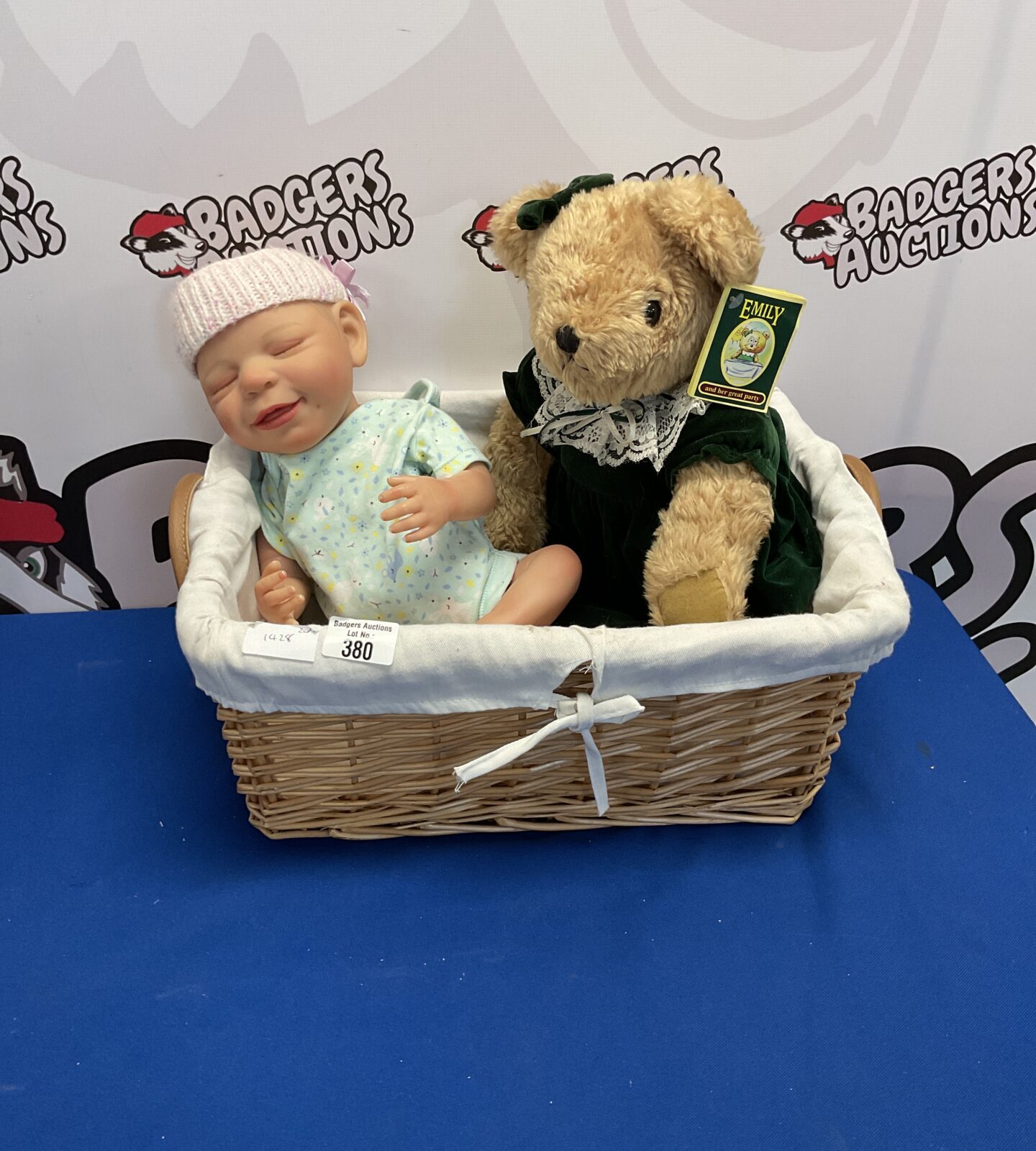 Wicker basket containing baby doll and emily teddy bear