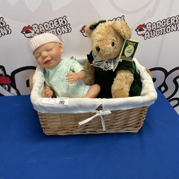 Wicker basket containing baby doll and emily teddy bear