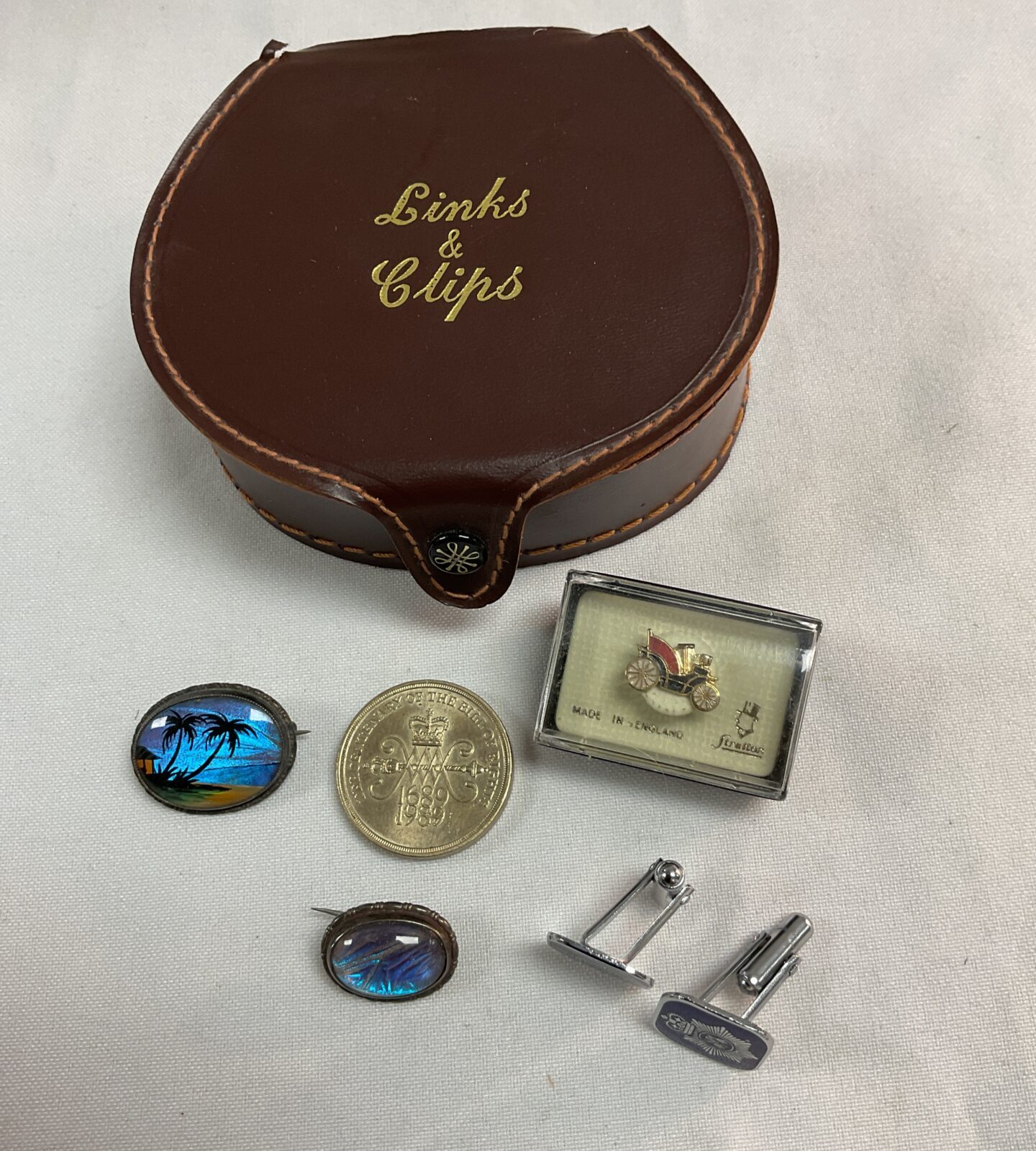 Leather links and clips box with two silver abalone brooches £2 coin cufflinks and car pin badge