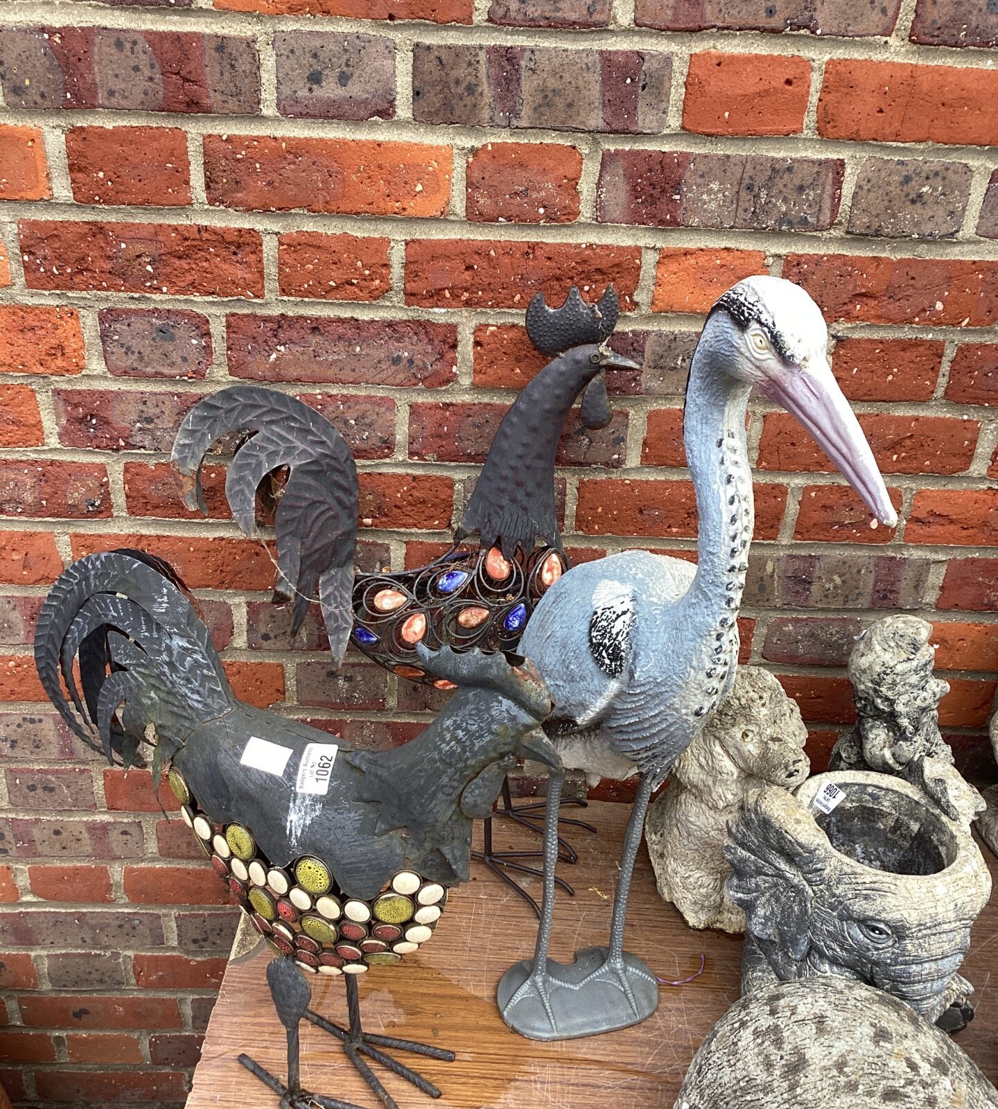 Two metal cockerels with plastic Heron garden ornaments