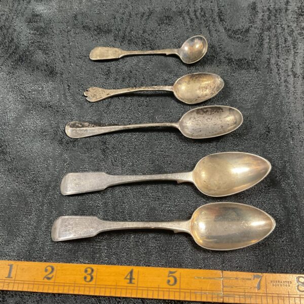 Antique silver spoon collection on dark background.