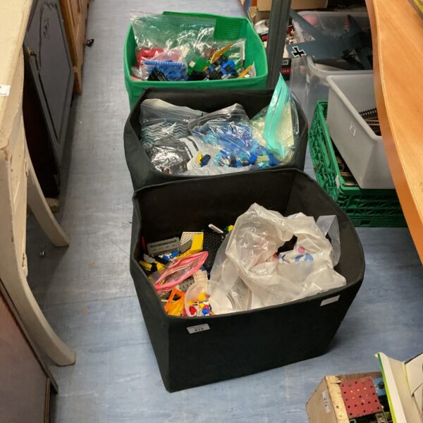 Three black boxes filled with mixed Lego building blocks.