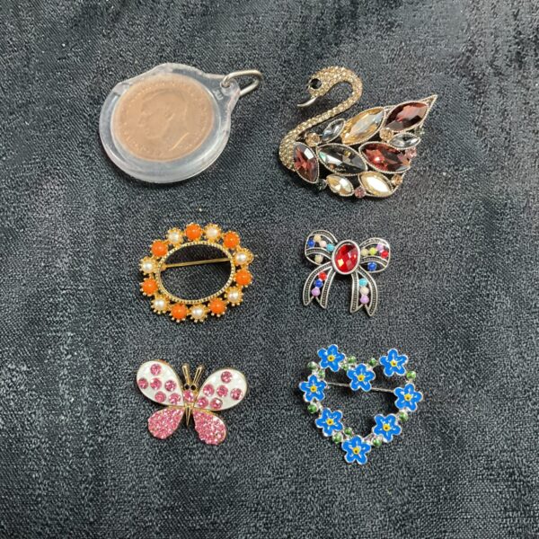 Five costume jewellery brooches and penny pendant