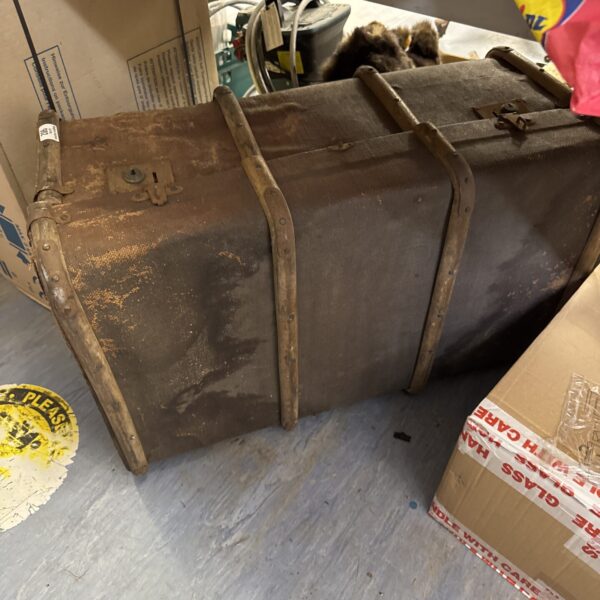 Front view of antique steamer trunk with metal hardware.