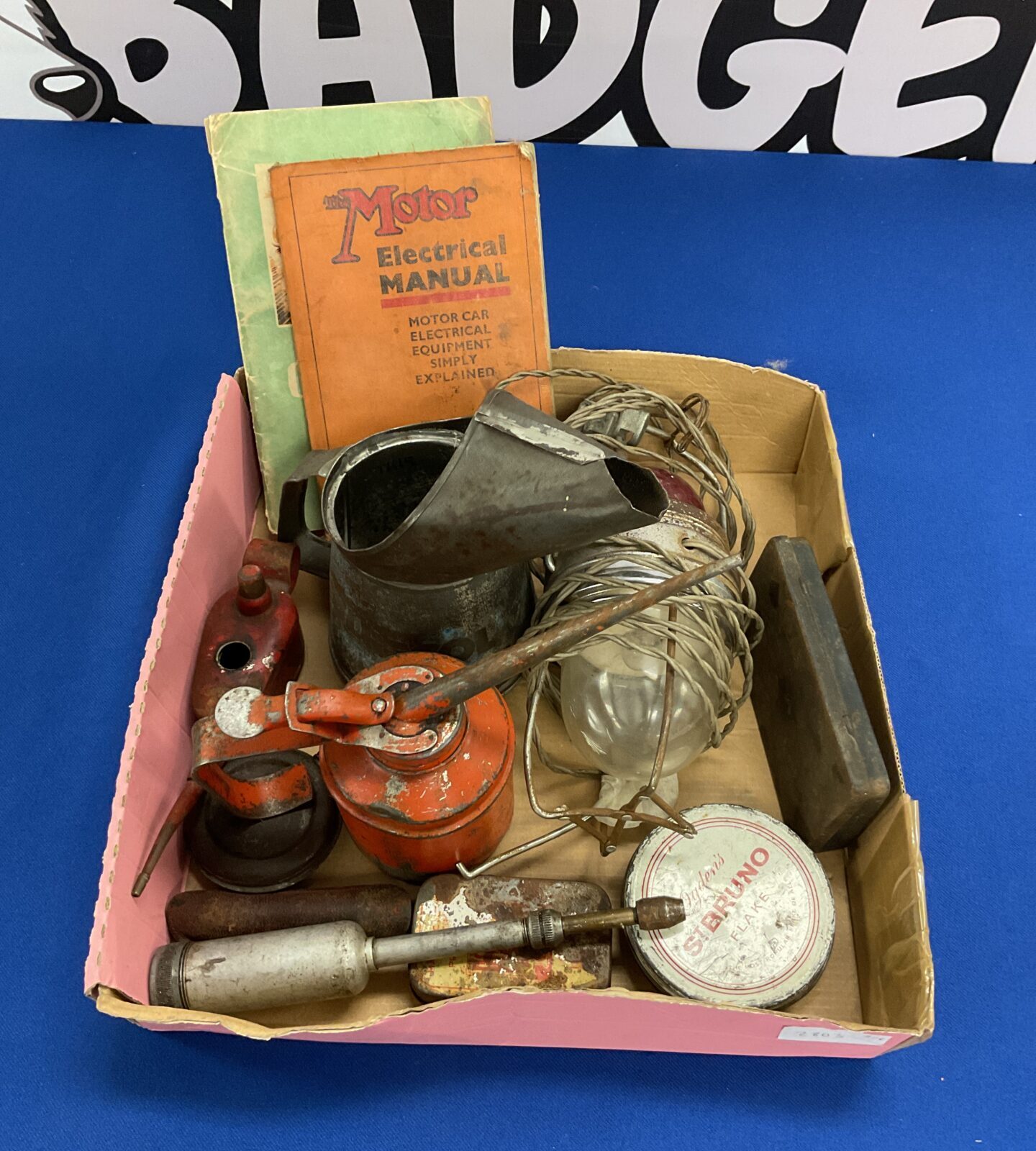 Collection of vintage oil cans grease gun and motor car booklets