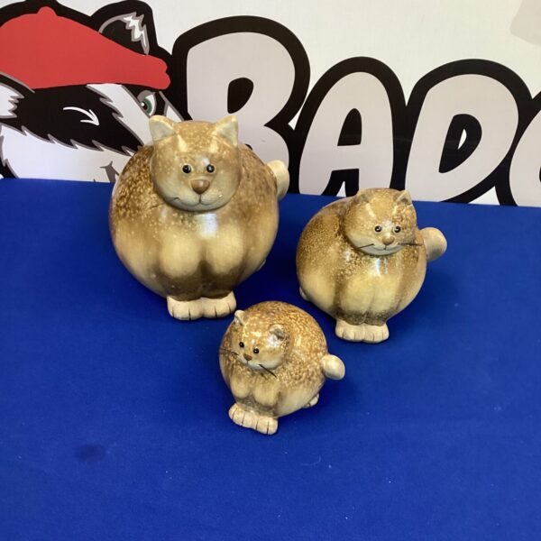 Three vintage porcelain cats displayed on a surface.