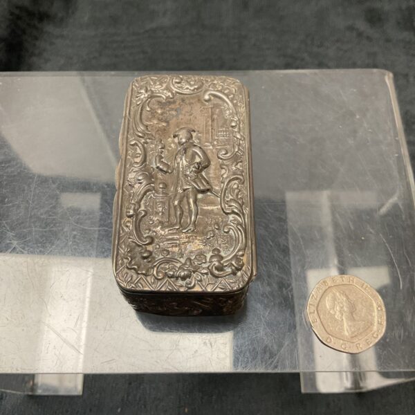 Antique silver pill box with detailed relief decoration.