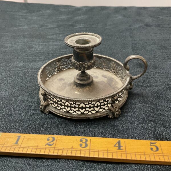 Antique silver chamberstick with intricate detailing and a handle.