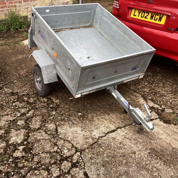 Silver aluminium trailer hitched to a red car.