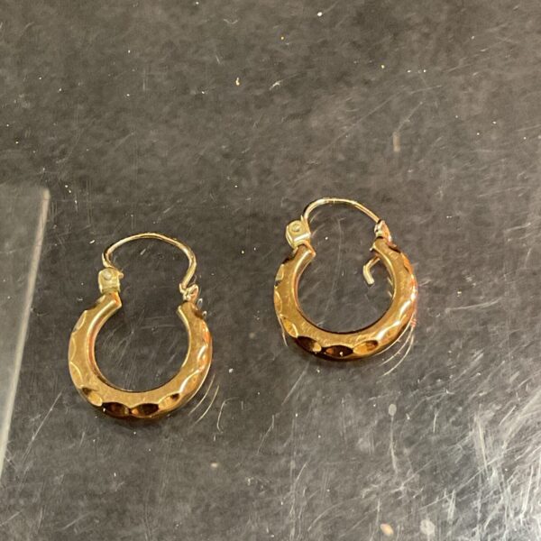 Close-up of 9ct gold hoop earrings with textured finish.