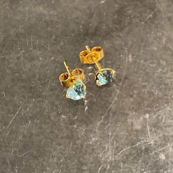 Close-up of 9ct gold aquamarine stud earrings with gemstone detail.