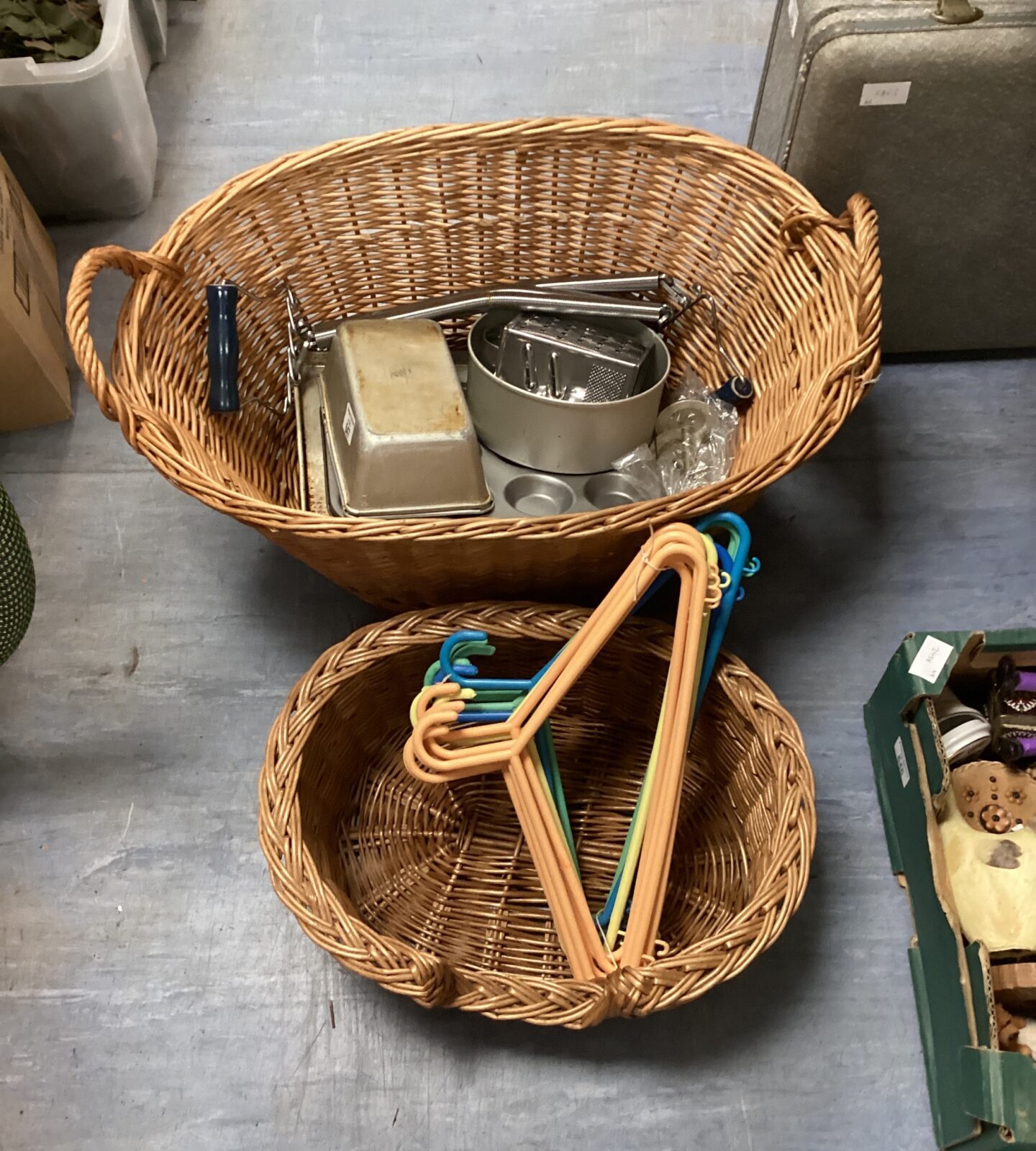 Two wicker baskets with assortment of baking trays & clothes hangers