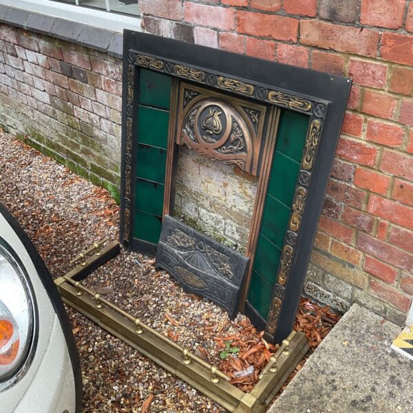 Antique Art Nouveau fireplace with decorative tiled inserts and brass fender.