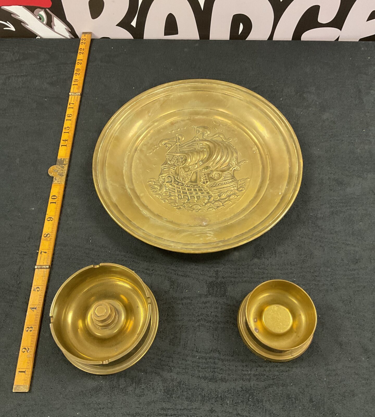 two brass cannon shell pindishes and brass relief of galleon decorated wall plate"