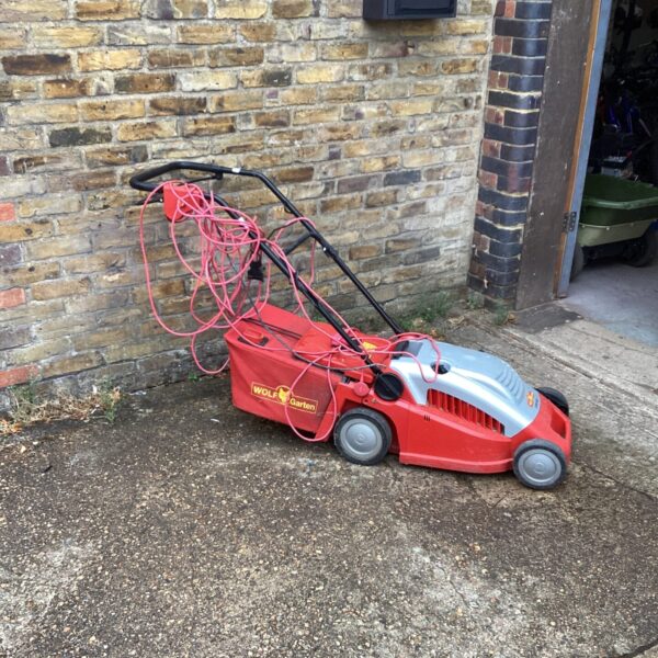 Red Wolf Garten electric lawn mower in a garden setting.