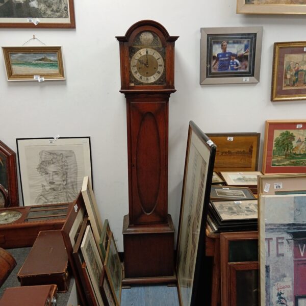 Antique grandmother clock in a room with other collectibles.