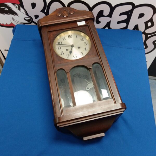 Antique oak wall clock with pendulum and Roman numerals.