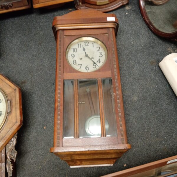 Vintage oak wall clock with pendulum and roman numerals.