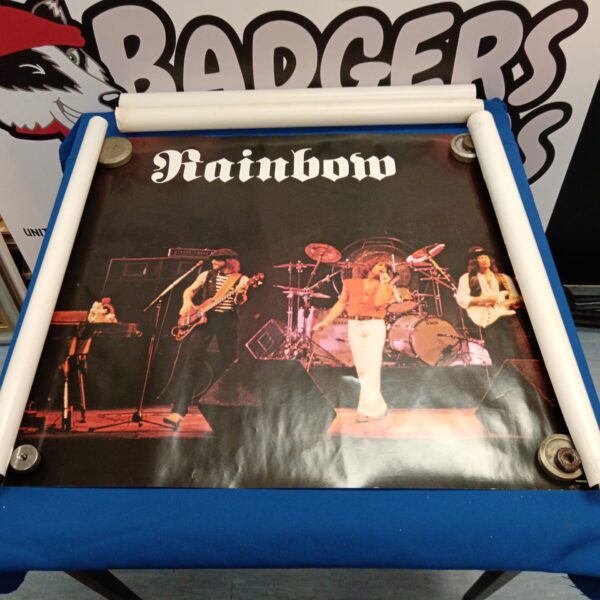 Vintage Rainbow rock band poster displayed on a blue stand.