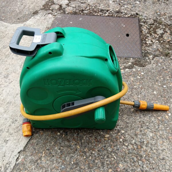 Green Hozelock hose reel in a garden setting.