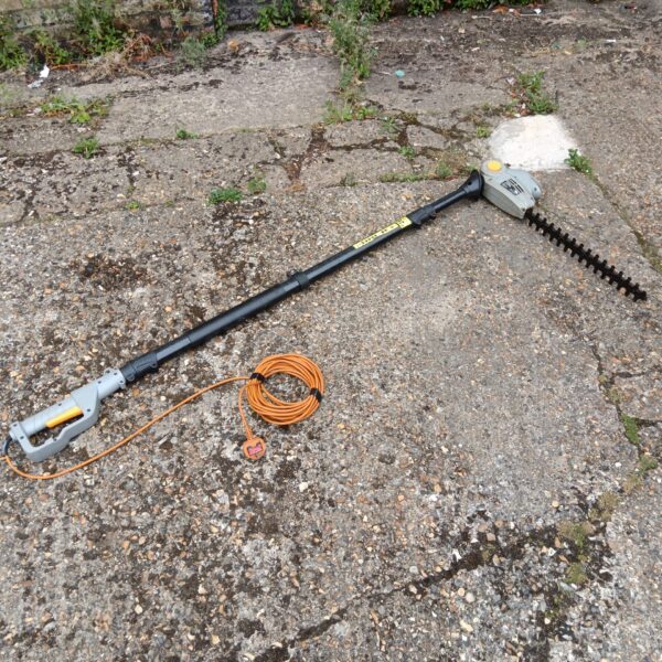Titan electric pole hedge cutter with extended reach for garden maintenance.