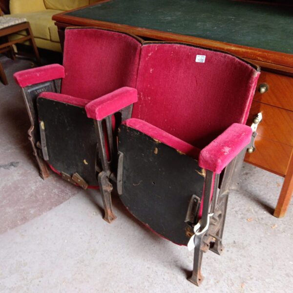 Pair of vintage red cinema seats with cast iron frames.