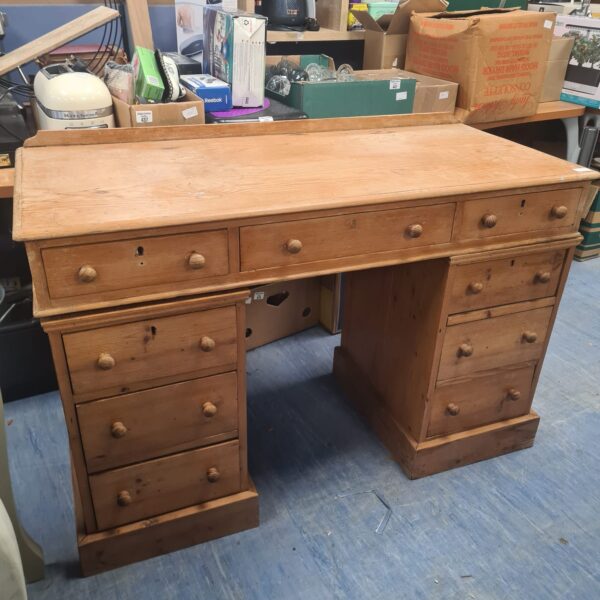 Front view of a large vintage pine desk with drawers.