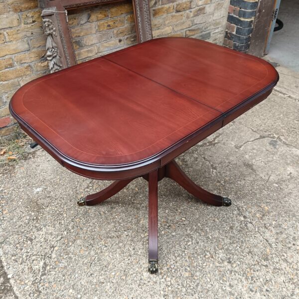 Dark wood oval dining table with claw feet.