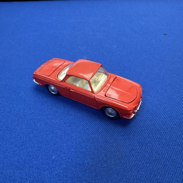 Red Corgi VW Karmann Ghia diecast car on blue background.