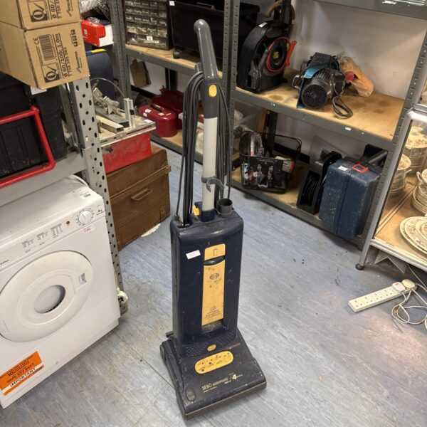 Sebo Automatic X4 vacuum cleaner with other items in background.