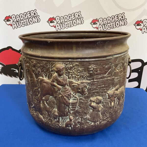 Vintage copper pot with milk maid design and lion head handles.