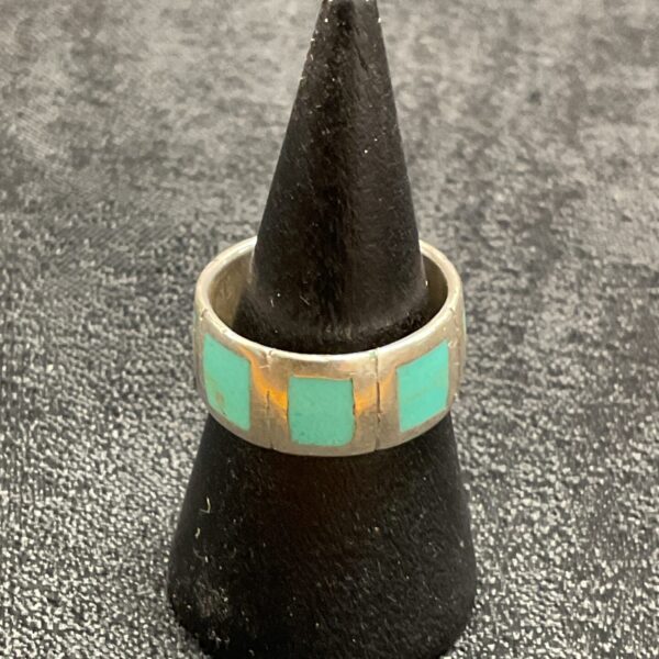 Close-up of a silver turquoise ring on a display stand.