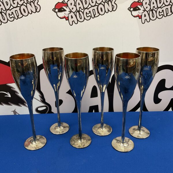 Set of six vintage silver plate champagne flutes on a dark surface.